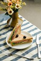 Mortadella and Multigrain Bread sandwich topping with black olive served in plate isolated on napkin side view of breakfast food photo