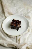 Chocolate Brownie served in plate isolated on napkin side view of cafe baked food on background photo