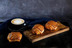 served on wooden board with cup of coffee latte art isolated on napkin side view of french breakfast baked food item on grey background photo