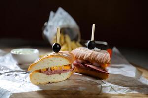 Robust Roast Beef Cheddar Sandwich with mayonnaise dip with fries served in wooden board isolated on napkin side view of breakfast food photo