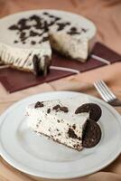 oreo tarta de queso rebanada incluir chocolate, crema, azúcar con tenedor y flores servido en plato aislado en servilleta lado ver de café comida foto