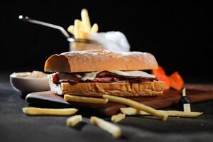 asado carne de vaca sub emparedado con francés papas fritas Cubeta servido en de madera tablero aislado en oscuro antecedentes lado ver de desayuno comida foto