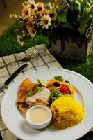 Grilled Jerk Spiced Fillet Fish with rice, dip and salad served in plate with knife and fork isolated on napkin side view of korean style meat food on gassy background photo