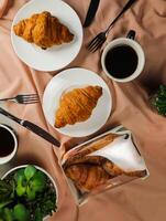 llanura cuerno servido en de madera tablero con taza de negro café aislado en servilleta con cuchillo y tenedor parte superior ver de francés desayuno horneado comida articulo en gris antecedentes foto