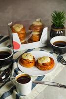 Cinnamon Roll served in plate with cup of black coffee with knife and fork isolated on napkin side view of french breakfast baked food item photo