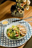 Caesar Salad or ceaser include chicken and spinach served in plate with flowers, knife and fork isolated on napkin side view of healthy green food on table photo