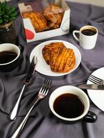 Peach Danish pastry puff served in plate with cup of black coffee isolated on napkin with fork and knife top view of french breakfast baked food item on grey background photo