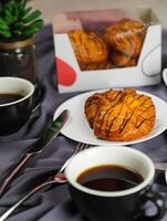 melocotón danés Pastelería soplo servido en plato con taza de negro café aislado en servilleta con tenedor y cuchillo lado ver de francés desayuno horneado comida articulo en gris antecedentes foto