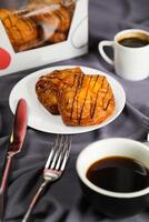 melocotón danés Pastelería soplo servido en plato con taza de negro café aislado en servilleta con tenedor y cuchillo lado ver de francés desayuno horneado comida articulo en gris antecedentes foto