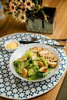 Caesar Salad or ceaser include chicken and spinach served in plate with flowers, knife and fork isolated on napkin side view of healthy green food on table photo
