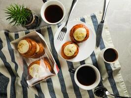 Cinnamon Roll served in plate with cup of black coffee with knife and fork isolated on napkin top view of french breakfast baked food item photo