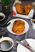 melocotón danés Pastelería soplo servido en plato con taza de negro café aislado en servilleta con tenedor y cuchillo lado ver de francés desayuno horneado comida articulo en gris antecedentes foto