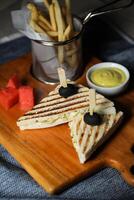 Grilled Chicken Sandwich with fries bucket served in wooden board isolated on napkin side view of breakfast food photo