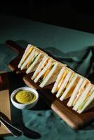 Assorted Club Sandwich isolated on wooden with mayonnaise dip and french fries bucket board side view of italian fast food on background photo