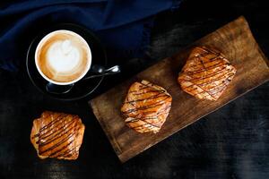 served on wooden board with cup of coffee latte art isolated on napkin top view of french breakfast baked food item on grey background photo