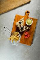 Grilled Chicken Sandwich with fries bucket served in wooden board isolated on napkin side view of breakfast food photo