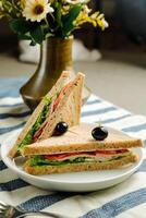 Mortadella and Multigrain Bread sandwich topping with black olive served in plate isolated on napkin side view of breakfast food photo