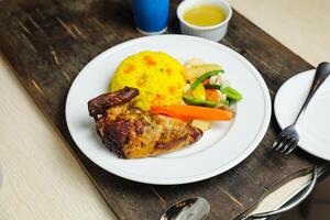 Rice with chicken Roast Meal with salad served in plate with sauce, cold drink, spoon and fork isolated on wooden board side view of thai food photo