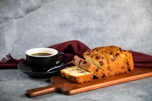 Mix Fruit Cake slice served on wooden board with cup of black coffee isolated on napkin side view of french breakfast baked food item photo