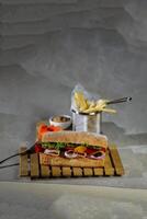 Ciabatta Smoked Ham Sandwich isolated on wooden with mayonnaise dip and french fries bucket board side view of italian fast food on grey background photo