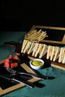 Assorted Club Sandwich isolated on wooden with mayonnaise dip and french fries bucket board side view of italian fast food on background photo