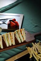 Assorted Club Sandwich isolated on wooden with mayonnaise dip and french fries bucket board side view of italian fast food on background photo