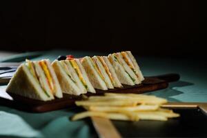 Assorted Club Sandwich isolated on wooden with mayonnaise dip and french fries bucket board side view of italian fast food on background photo