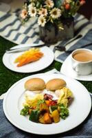 Egg Benedict slider with vegetable salad include tomato, potato, lettuce leaf and carrot with tea, coffee, and sweet melon served on food table top view healthy english breakfast photo