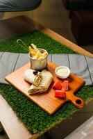 Naga Beef egg wrap roll filled with tomato, onion, cucumber with french fries, mayo and watermelon slice dip served on wooden board top view of fastfood appetizer photo