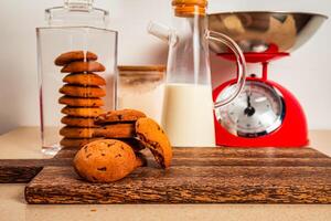 Tasty Chocolate cookie with jug of milk served on wooden board side view of healthy breakfast on table photo