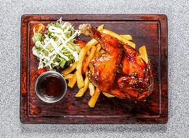 bbq spring chicken with fries, salad and sauce served in wooden board isolated on background top view of hong kong food photo