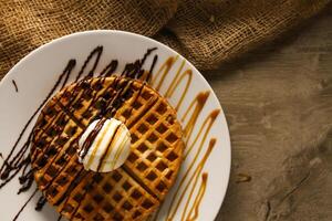 Waffle with Ice Cream, Caramel and Chocolate served in dish isolated on table top view of cafe snack photo