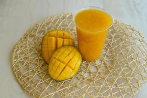 Fresh Mango Juice served in disposable glass isolated on table side view of healthy morning juice drink photo