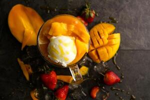 Rose mango shake with strawberry and ice cream scoop served in jar isolated on table top view of healthy morning juice drink photo