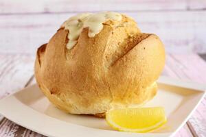 Soup in Bread Bowl with lemon slice served isolated on table closeup top view of hot soup photo