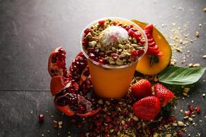 strawberry mango and pomegranate juice with nuts pistachio and cashew nut served in disposable glass isolated on table side view of healthy drink photo