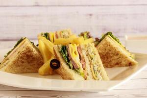 CLUB SANDWICH with olive and french fries served in dish isolated on table closeup side view of fastfood photo