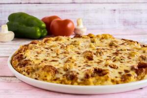 Mozzarella Pizza topping with capsicum, mushroom, tomato and olives served in dish isolated on table side view of arabic fastfood photo