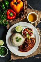 Jamaican Mutton gravy with plain rice, salad, tomato, cucumber dip, sauce and bell pepper served in plate isolated on napkin top view of lunch food photo