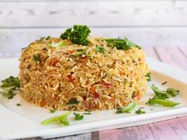 BASIL FRIED RICE with Broccoli, Coriander, carrot and herbs served in isolated on wooden table closeup side view of fastfood photo