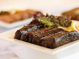 Garpes VINE LEAVES wrap rolls served in dish isolated on wooden table top view of cold mazza arabic food photo