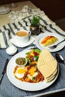 Shakshouka with vegetable salad include tomato, potato, lettuce leaf and carrot with tea, coffee, and sweet melon served on food table top view healthy breakfast photo