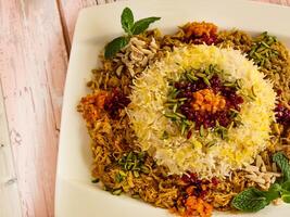 ZERESHK POLO WITH CHICKEN topping with pistachio, peanuts, mint and fried onion served in dish isolated on table closeup top vie of arabic spicy food photo