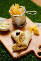 Classic Cajun Beef Double Cheese wrap roll filled with tomato, onion, cucumber with french fries, mayo dip served on wooden board top view of fastfood appetizer photo