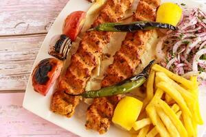 Chicken Seekh kabab with minced meat, lemon, onion and french fries served in dish isolated wooden table top view of tandoori grill bbq food photo