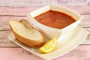 TOM YUM SOUP with bread and lemon slice served in bowl isolated on table closeup top view of hot soup photo