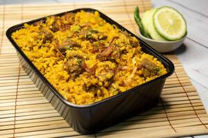 beef khichuri biryani rice pulao with cucumber and lemon slice served in dish isolated on wooden table closeup side view of bangladeshi and indian spicy lunch food photo