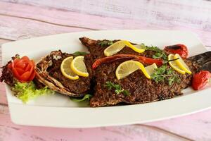 A la parrilla mar bajo pescado con limón rebanada y tomate servido en plato aislado en mesa de cerca parte superior ver de A la parrilla Mariscos foto