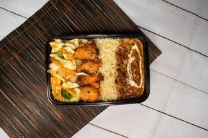 chicken tikka and pulao with Dal Makhani biryani rice with cucumber, dip sauce and lemon slice served in dish isolated on wooden table top view of bangladeshi and indian spicy lunch food photo