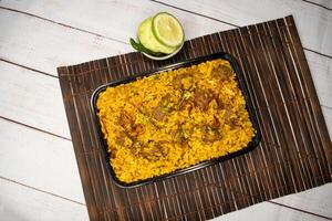 beef khichuri biryani rice pulao with cucumber and lemon slice served in dish isolated on wooden table closeup top view of bangladeshi and indian spicy lunch food photo